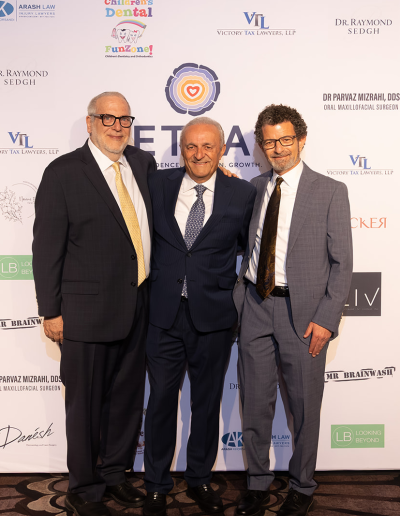 3 men posing together in front of the event backdrop.