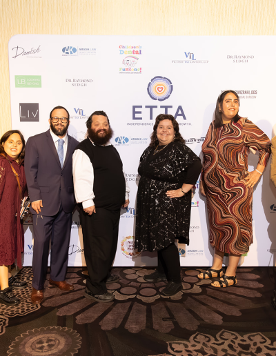 7 people posing in front of the event backdrop.