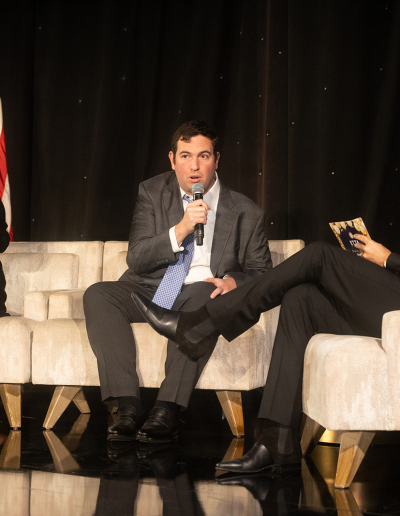 Panel discussion on stage with 3 people seated on chairs.