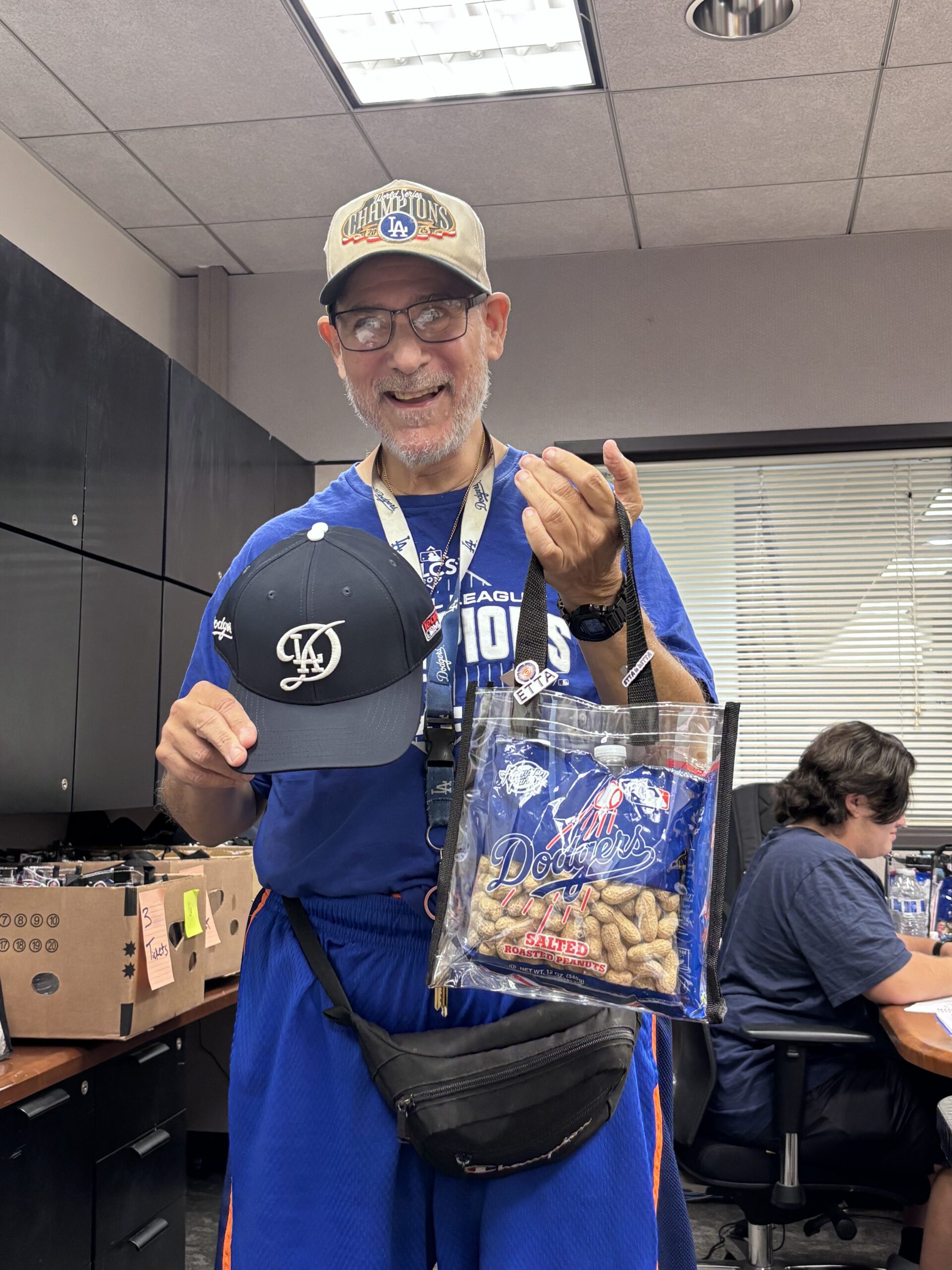 man wearing dodgers gear holding dodgers goodie bag at etta office